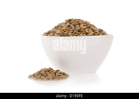 Lentilles brunes dans un bol isolé sur fond blanc Banque D'Images