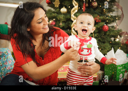 Jeune femme ethnique attrayant avec son nouveau-né Près de l'arbre de Noël. Banque D'Images