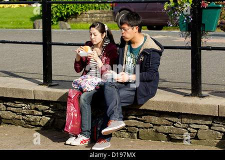 Les touristes japonais de la Bowness Bay sur le lac Windermere Cumbria Lake District National Park Banque D'Images