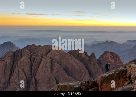 Une personne regarde le lever du soleil depuis le bord d'une falaise au sommet du mont Sinaï dans le désert du Sinaï Banque D'Images