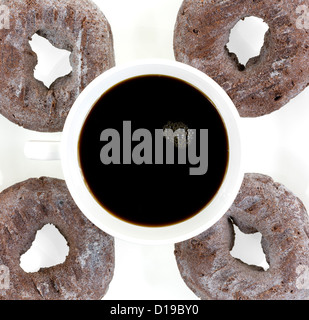 Une tasse de café noir avec quatre beignets sur une plaque blanche. Banque D'Images