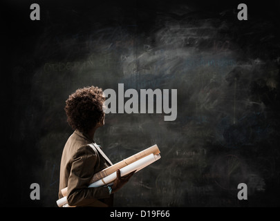 Businesswoman holding blueprint par blackboard Banque D'Images