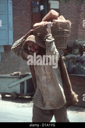 Cachemire, Srinagar - ragged homme porte en briques panier sur ses épaules Banque D'Images