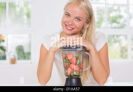 Smiling woman mettant les mains sur le mélangeur Banque D'Images
