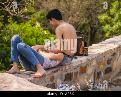 Un garçon et fille, jeunes amoureux, enbrace sur un mur de pierre du tres Caras de Indios monument à Tobati, au Paraguay. Banque D'Images