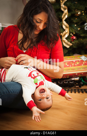 Jeune femme ethnique attrayant avec son nouveau-né Près de l'arbre de Noël. Banque D'Images