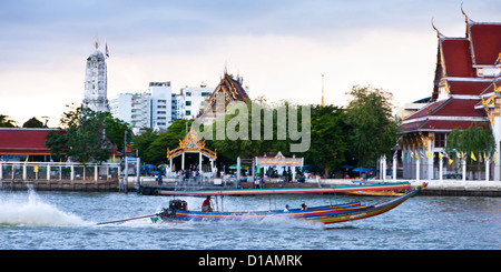 Une longue queue vitesses bateau devant le temple de cloches sur le Chao Phraya, Bangkok Banque D'Images