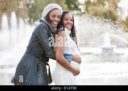 Portrait of happy young woman embracing pregnant woman from behind Banque D'Images