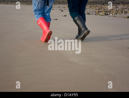 Deux femmes marchant le long de la plage en hiver, le port de bottes. Shot de wellies. Corps de shot. Banque D'Images