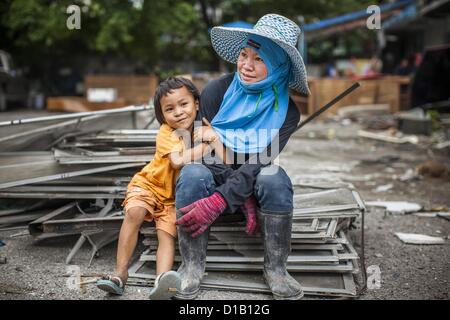 Le 12 décembre 2012 - Bangkok, Thaïlande - un travailleur de démolition et sa fille au ''Washington Square'' un célèbre quartier des divertissements de Sukhumvit Soi 22 à Bangkok. Les travailleurs du chantier de démolition sur de nombreux projets en Thaïlande en direct sur leur site d'abattre l'édifice et de recyclage que peut-recyclés comme ils le font jusqu'à ce que le site n'est plus habitable. Ils dorment sur les étages des bâtiments ou parfois dans des tentes, la cuisson au gaz ou des réchauds à charbon travaillant du matin au soir. Parfois les familles vivent et travaillent ensemble, d'autres fois seulement les hommes. Washington Square est l'un des plus ancien de Bangkok ligh rouge Banque D'Images