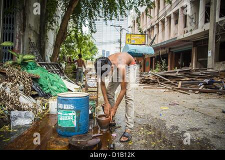 Le 12 décembre 2012 - Bangkok, Thaïlande - démolition d'un travailleur ne ses plats après le travail sur un équipage de démolition à ''Washington Square'' un célèbre quartier des divertissements de Sukhumvit Soi 22 à Bangkok. Les travailleurs du chantier de démolition sur de nombreux projets en Thaïlande en direct sur leur site d'abattre l'édifice et de recyclage que peut-recyclés comme ils le font jusqu'à ce que le site n'est plus habitable. Ils dorment sur les étages des bâtiments ou parfois dans des tentes, la cuisson au gaz ou des réchauds à charbon travaillant du matin au soir. Parfois les familles vivent et travaillent ensemble, d'autres fois seulement les hommes. Washington Square a été o Banque D'Images