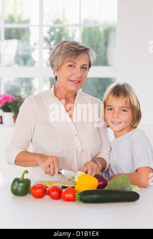 Granny couper des légumes avec son petit-fils Banque D'Images