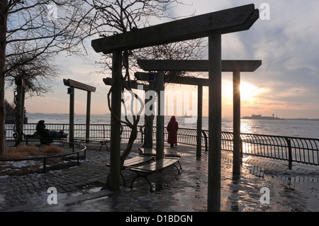 Coucher du soleil d'hiver au sud Cove, Battery Park City avec la Statue de la Liberté et Ellis Island à l'horizon Banque D'Images