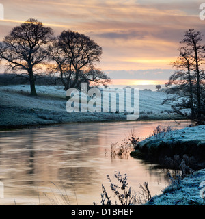 La rivière en crue à Derwent Bridge Howsham, Yorkshire du nord, au coucher du soleil en plein hiver. Banque D'Images