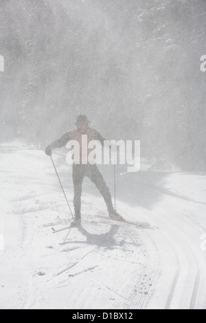 Skieur effectue un zoom avant sur un skate piste de ski avec la neige qui tombe autour de lui comme il va. Banque D'Images