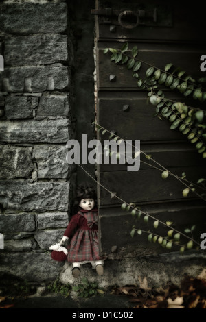 Une vieille poupée, assis dans une vieille porte en bois Banque D'Images