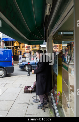 Totnes, Devon, Angleterre. Le 12 décembre 2012. Musicien ambulant aux portes d'une librairie du chant dans un microphone. Banque D'Images