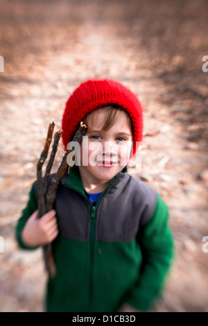 Petit garçon en molleton et red hat passe une randonnée et la collecte de bois de feu Banque D'Images