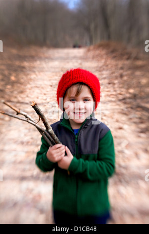 Petit garçon en molleton et red hat passe une randonnée et la collecte de bois de feu Banque D'Images