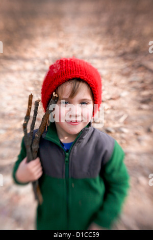 Petit garçon en molleton et red hat passe une randonnée et la collecte de bois de feu Banque D'Images