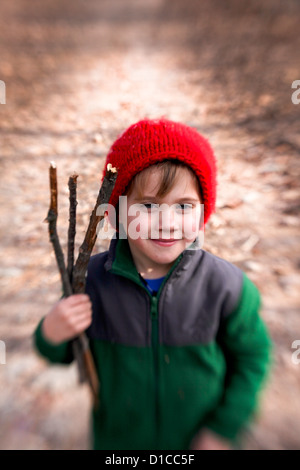 Petit garçon en molleton et red hat passe une randonnée et la collecte de bois de feu Banque D'Images