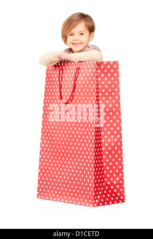 Un enfant souriant posant dans un rouge panier isolés contre fond blanc Banque D'Images