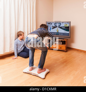 Un garçon de 13 ans de jouer sur une console Nintendo Wii Fit board avec Brother watching Banque D'Images