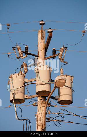 Une vue rapprochée de trois transformateurs sur un poteau électrique avec ciel bleu en arrière-plan. Banque D'Images