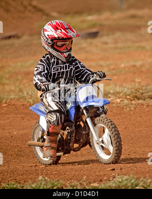 Jeune garçon - 5 ans - le port de vêtements protecteurs et l'équitation casque moto sur un chemin de terre Banque D'Images