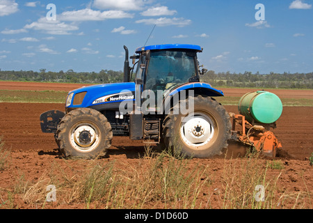 Tracteur charrue labour / domaine de la terre rouge, sous un ciel bleu Banque D'Images