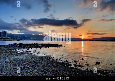Coucher du soleil sur une plage rocheuse à Hong Kong. Banque D'Images