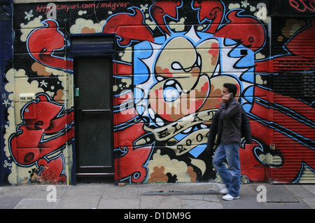 Homme marchant passé mur de graffiti, Londres Banque D'Images