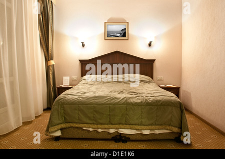 Lit double confortable dans une chambre d'hôtel Banque D'Images