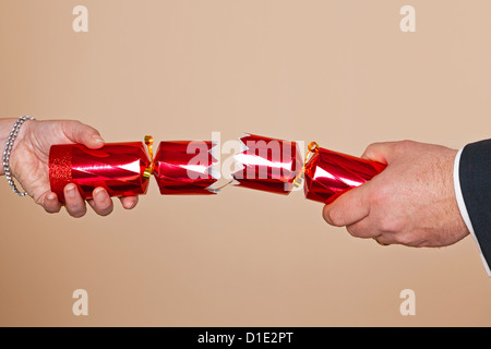 Un homme et femme mains tirant une red Christmas cracker.