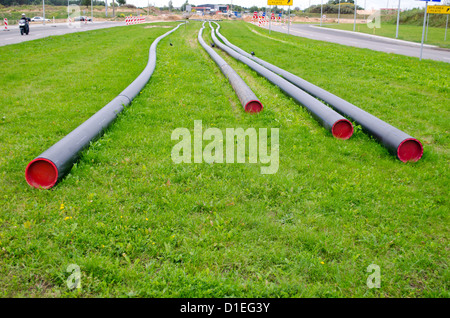 Les fils des câbles d'électricité avec tube de protection mise sur vert grassmeadow entre Road. L'industrie de la construction de la communication. Banque D'Images