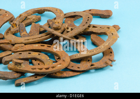 Pile de vieux rétro chaussures de cheval sur fond bleu Banque D'Images