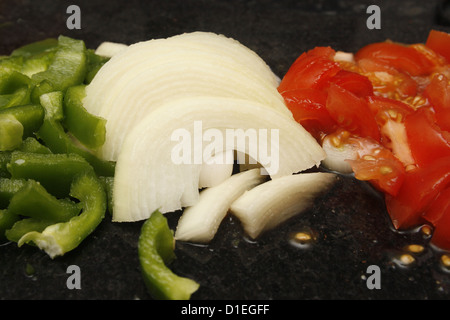 Poivrons verts, hachés, tomates et oignons blancs sur en planche à découper Banque D'Images