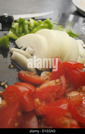 Poivrons verts, hachés, tomates et oignons blancs sur en planche à découper Banque D'Images