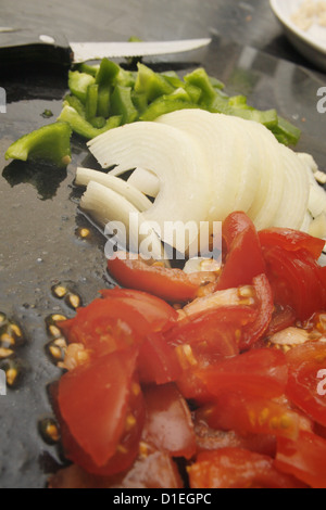 Poivrons verts, hachés, tomates et oignons blancs sur en planche à découper Banque D'Images