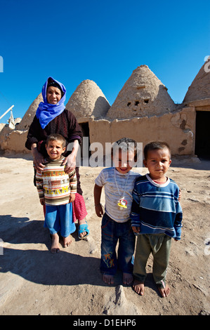 Les enfants arabes en face de la ruche' 'brique adobe de forme conique et de tholos maison d'Harman, Turquie Banque D'Images