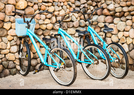 Trois vieilles bicyclettes bleu rouillé, stationné près d'un mur de pierre Banque D'Images