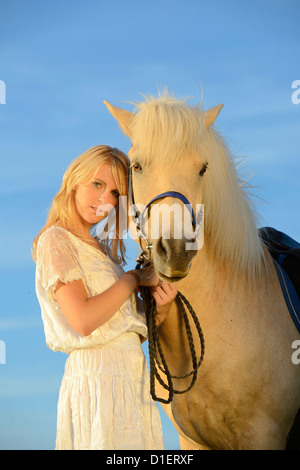 Jeune femme en robe blanche avec cheval sous ciel bleu Banque D'Images