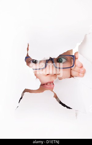 Spectacles pour enfants curieux dans l'air à travers un trou dans du papier blanc Banque D'Images