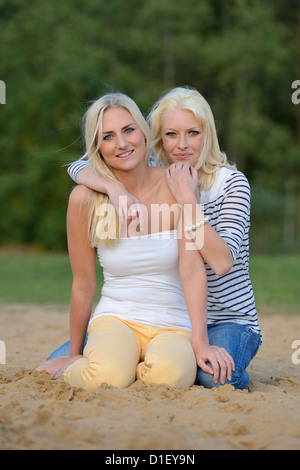 Deux jeunes femmes blondes heureux on sandy beach Banque D'Images