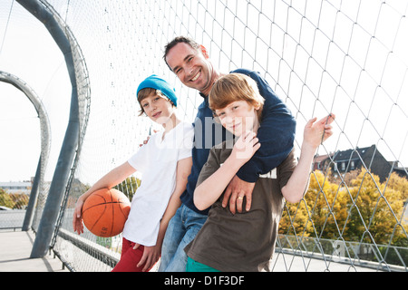 Son père et ses deux fils avec le basket-ball sur le terrain de sport Banque D'Images