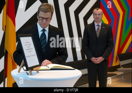 Le ministre des Affaires étrangères allemand Guido Westerwelle signe le livre de condoléances pour les victimes de la rampage en France à l'Ambassade américaine tandis que l'ambassadeur américain Philip Murphy se tient derrière lui à Berlin, Allemagne, 18 décembre 2012. 26 personnes et le tireur est mort lors d'un saccage d'une école primaire de Newtown, dans le Connecticut aux États-Unis. Photo : MARC N.R.I.T. Banque D'Images