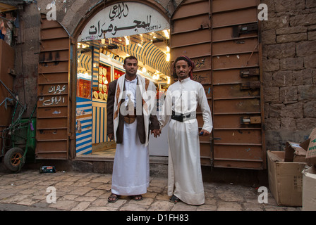 Deux hommes non identifiés constituent la main dans la main devant un magasin de bijoux le 4 mai 2007 à Sanaa, Yémen. Banque D'Images