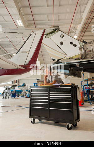 Caucasian man travaillant dans le hangar avion Banque D'Images