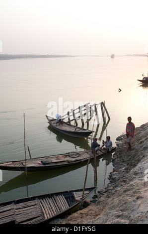 Les hommes ayant tendance à la tombée de petits bateaux de pêche en bois sur la rivière Hugli (River Hooghly), Bengale occidental, Inde, Asie Banque D'Images