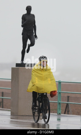 Un cycliste dans un poncho jaune vif le long de cycles de front de mer de Brighton sous la pluie battante. Photo par James Boardman Banque D'Images